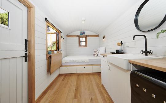 Elegant tiny house interior combining a bedroom and kitchen space with stylish furnishings and ample natural light