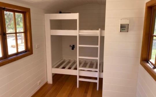 Cozy bunk bed setup in a tiny house at Eldorado, featuring wooden frames and natural light