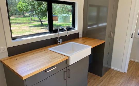 Compact and stylish tiny house kitchen with a large window and modern amenities