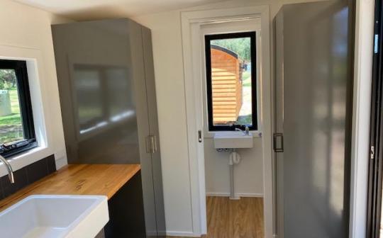 Inside view of a tiny house at Eldorado showing the kitchen counter and the open doorway leading outside