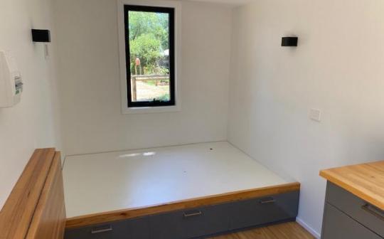 Minimalist tiny house interior with a large window overlooking serene greenery